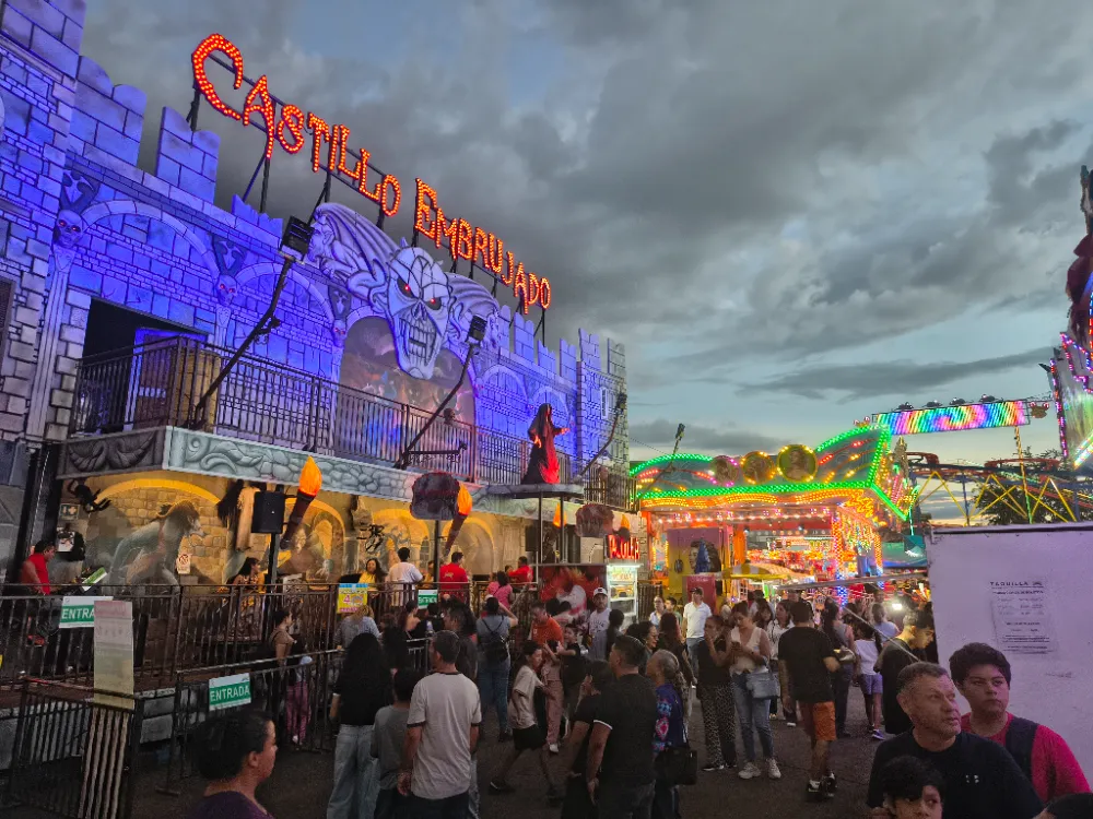 Fachada iluminada del Castillo Embrujado en las Fiestas de Octubre de Guadalajara, con visitantes formados en la entrada
